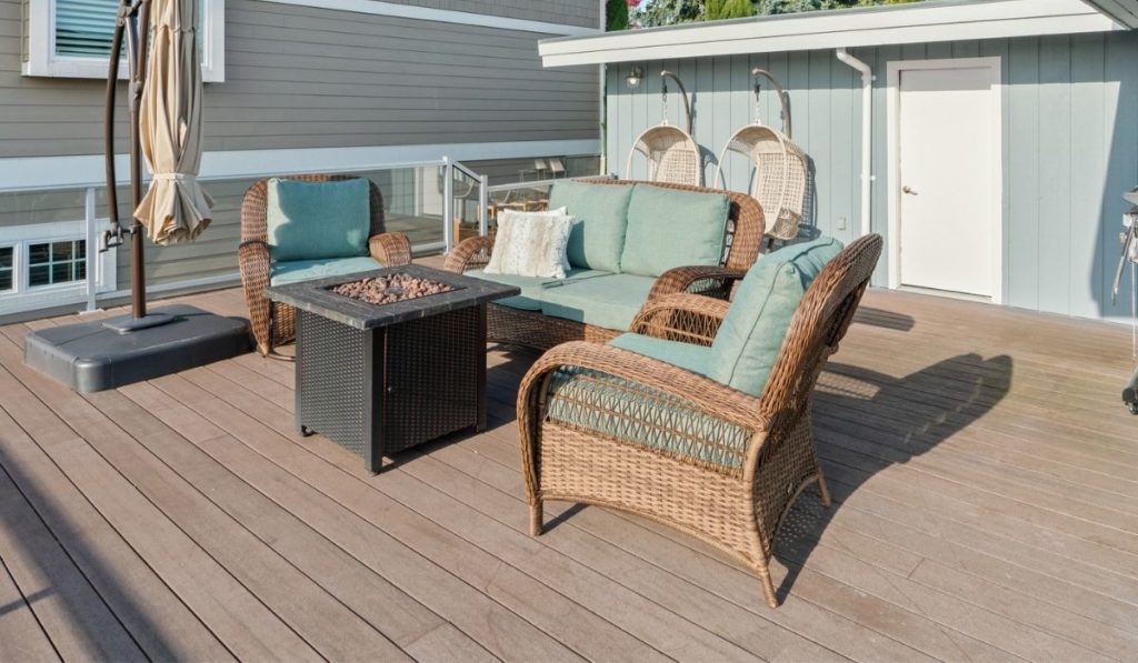 Wicker outdoor chairs and a fire pit on a wooden deck with a nice view of blue sky