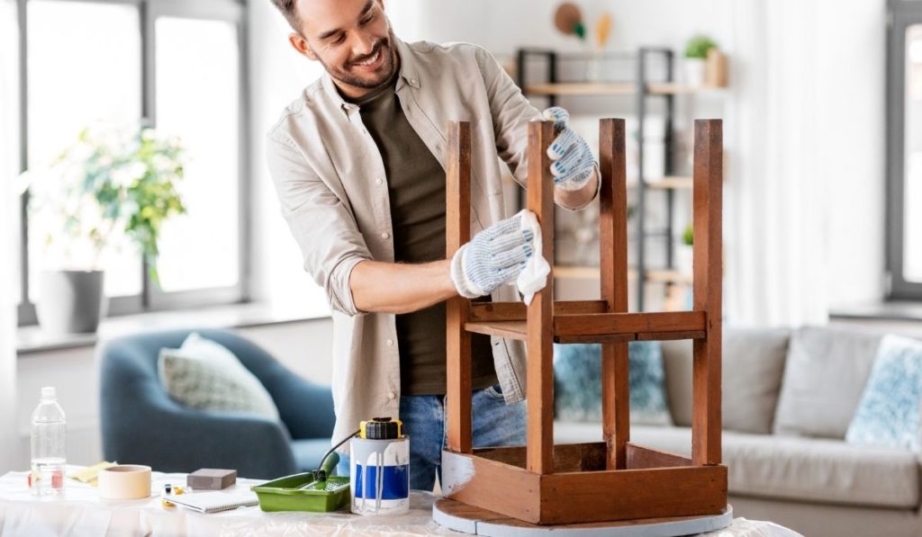 man cleaning old table surface with tissue