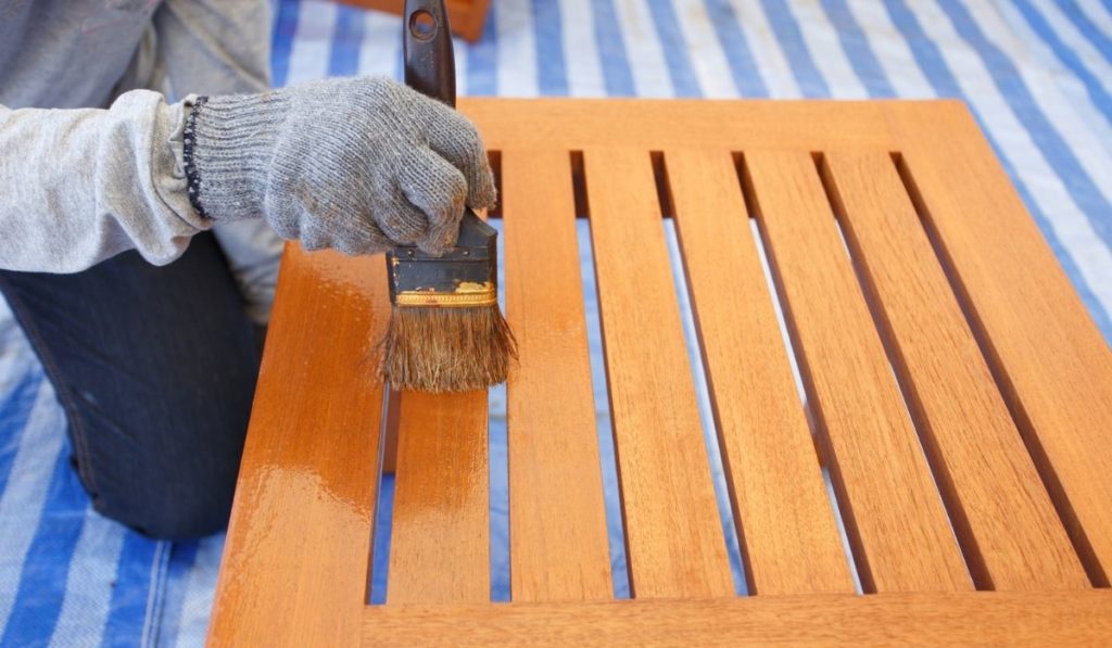 Brush in hand and painting on the wooden furniture 