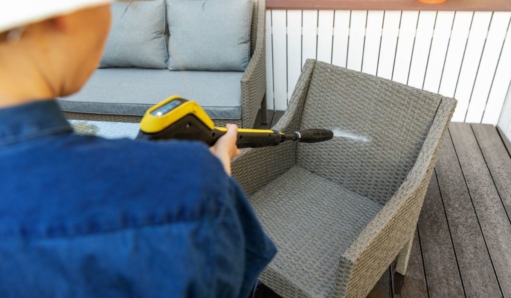 Woman doing garden terrace furniture cleaning with high pressure washer 