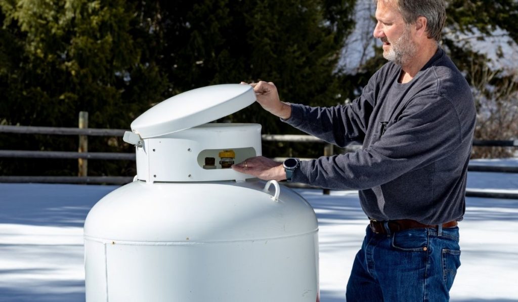 Outdoor man in winter prepares to open propane tank valves