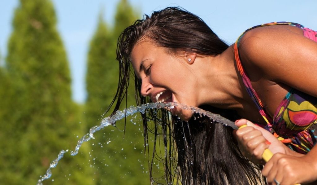 Girl drinking water from a hose