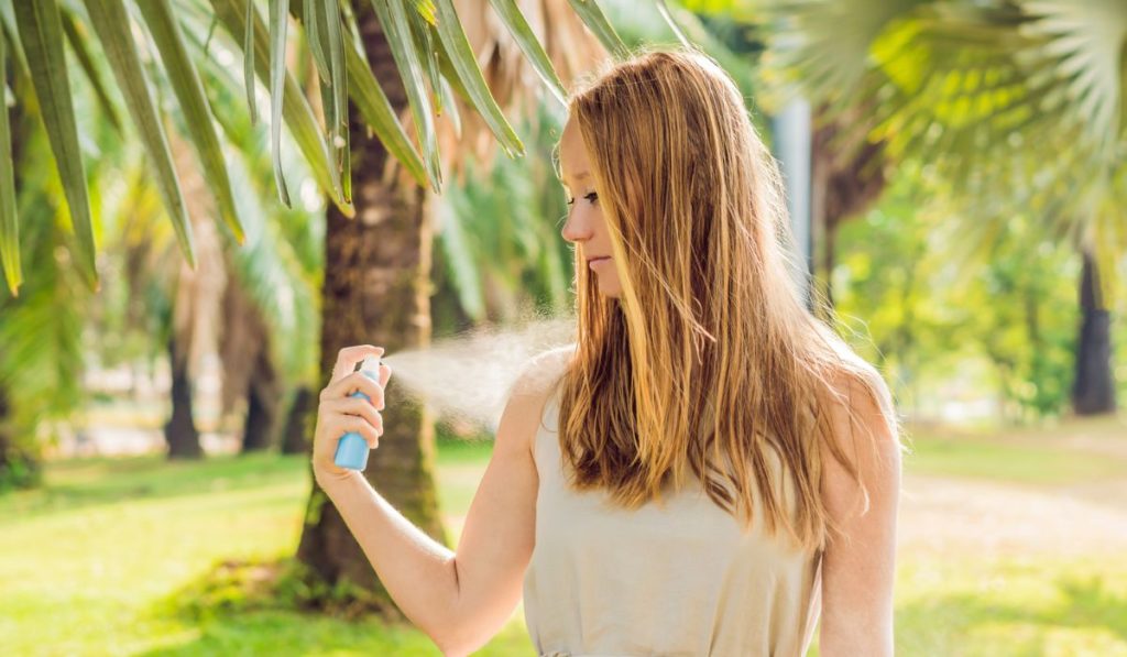 Woman spraying insect repellent on skin outdoor 