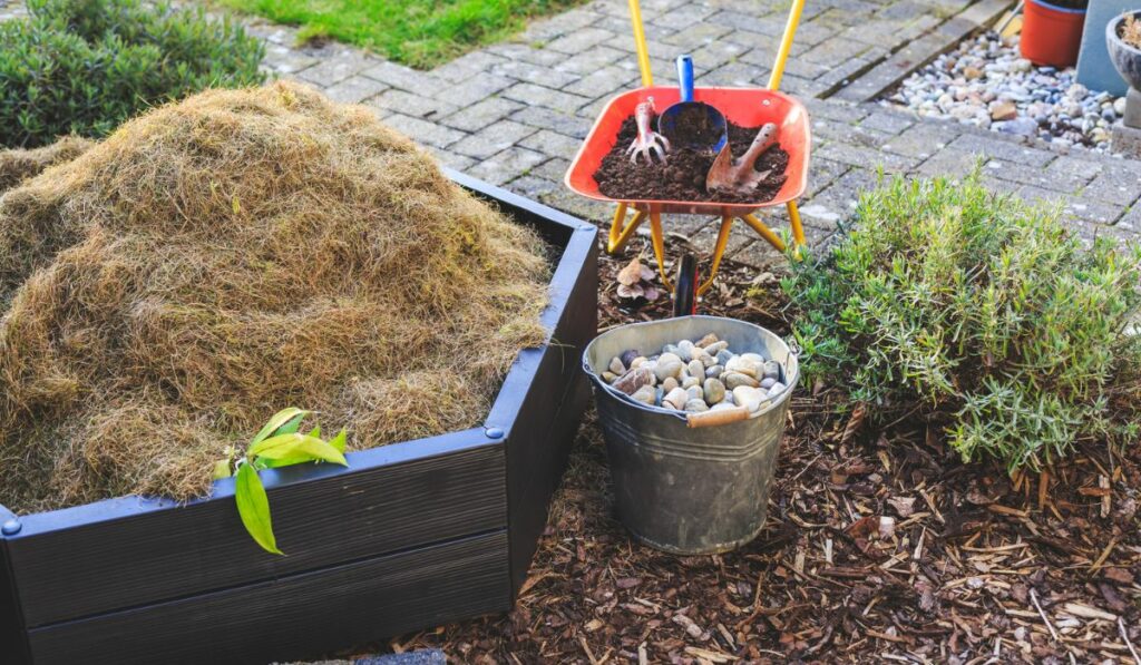 Bucket with stones and wheelbarrow with soil