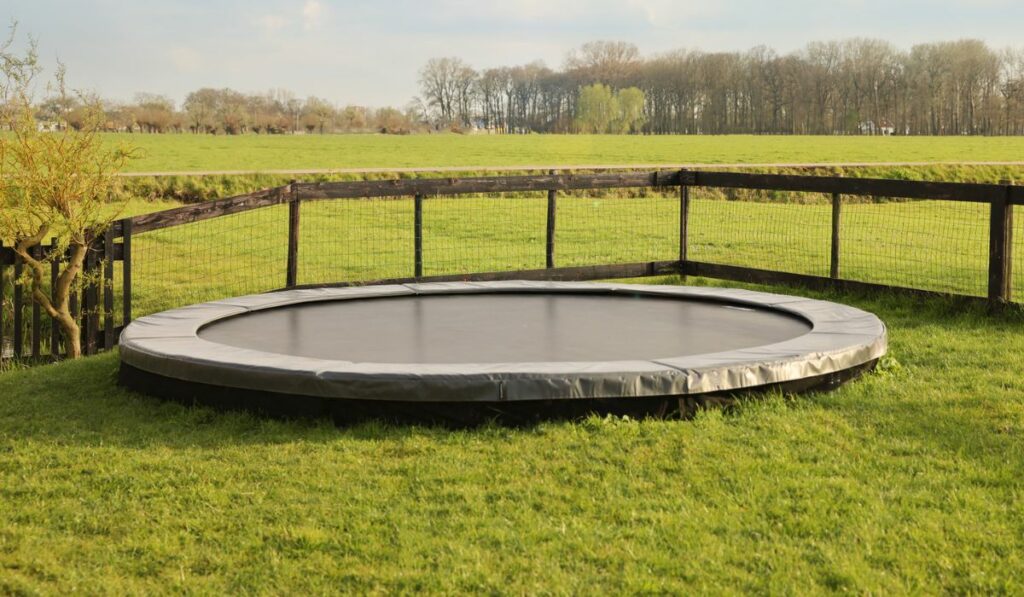 Croquet equipment and shoes near trampoline on green grass outdoors