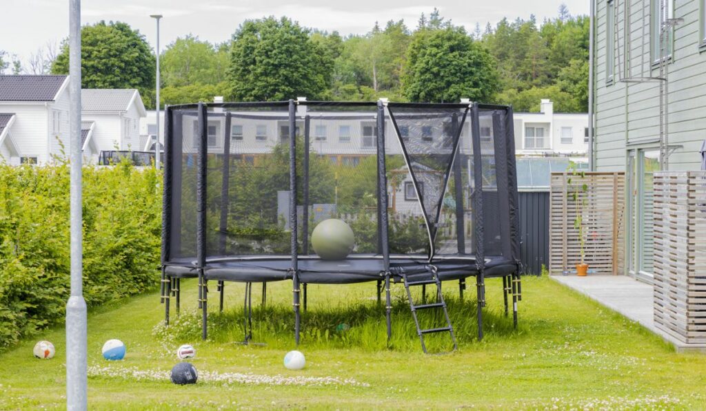 Trampoline with safety net mounted on backyards with football balls